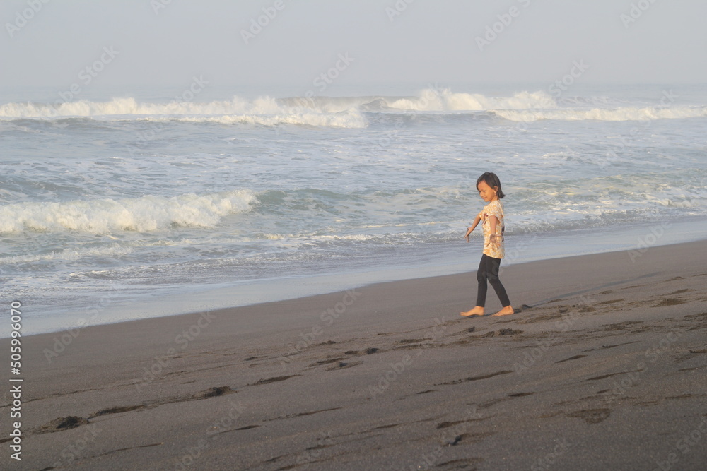 Girl alone on the beach, walking barefoot on the sand