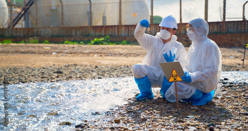 Team scientist in protective suit, mask and gloves collect sample of fish and dirty water from factory  took a sample of waste water for analysis. Pollution and environment problems