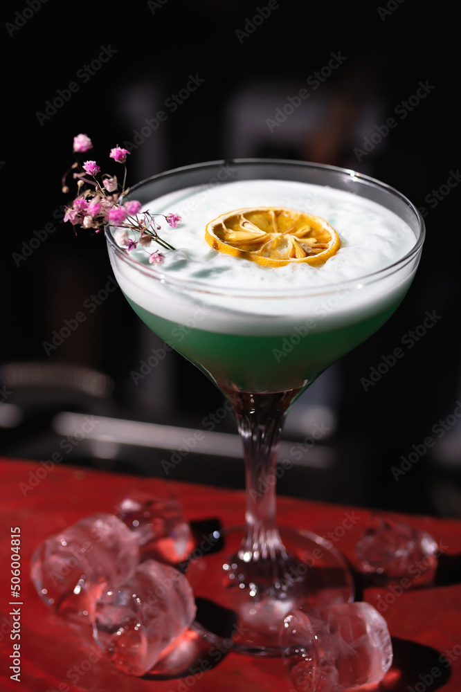 Close-up of an alcoholic cocktail with an orange, decorated with a flower and ice in a nightclub, bar Close-up of an alcoholic cocktail with an orange, decorated with a flower and ice in a nightclub, bar