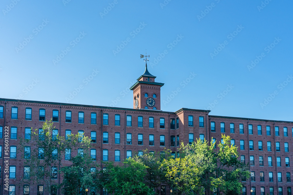 Historic cotton factory building with a clock tower in an old industrial park in Nashua, New Hampshire, USA at sunset.