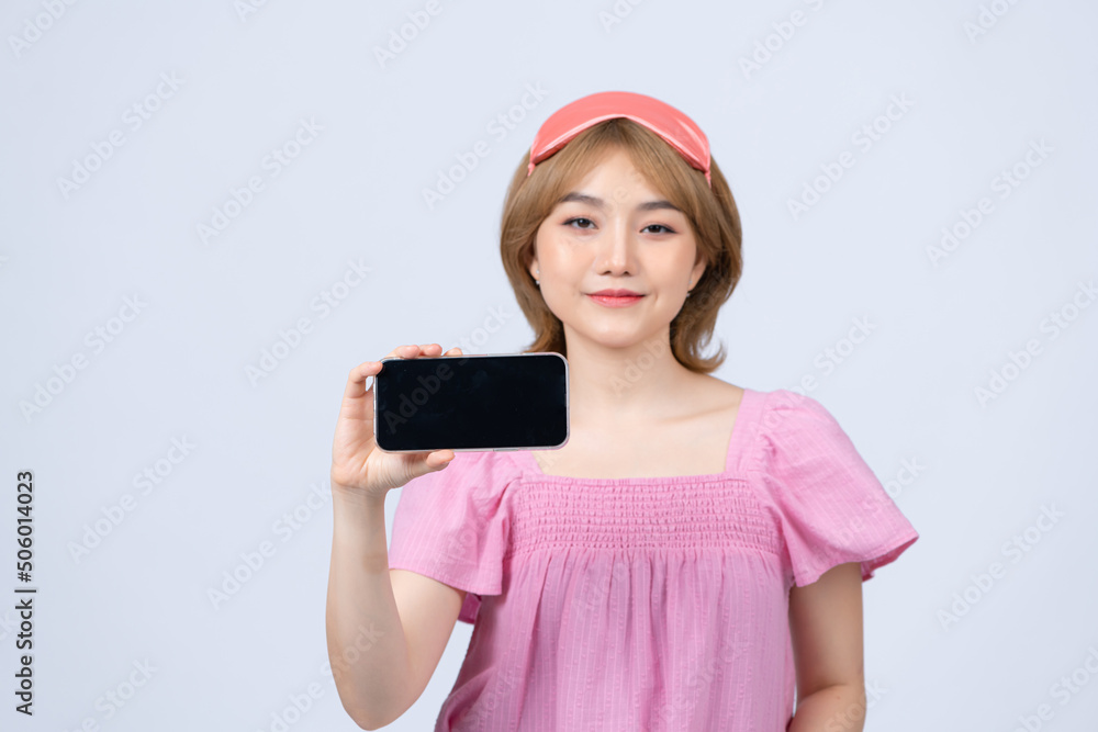cheerful smiling woman hold in hand mobile smartphone with blank black screen wearing sleep mask isolated on white background cheerful smiling woman hold in hand mobile smartphone with blank black screen wearing sleep mask isolated on white background