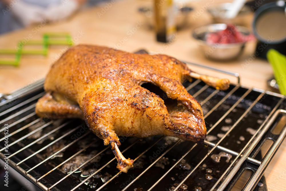 Baked duck on a rack and tray from the oven. The cooked duck cools