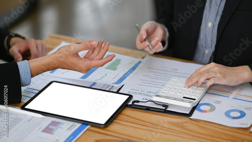 Cropped shot business colleagues discussing project strategy while having conversation on financial data report together