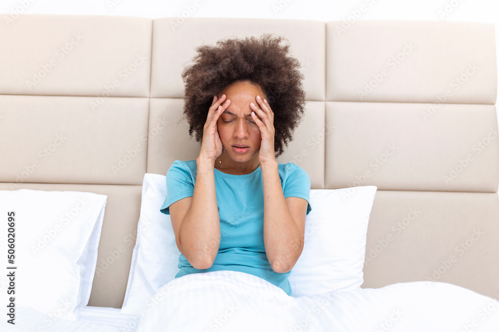 Φωτογραφία Portrait of an attractive black woman in bed at home with a headache, feeling pain and with an expression of being unwell