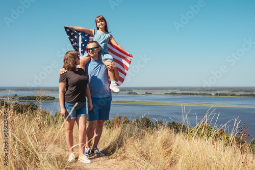 Happy family with american flag enjoying nature on a sunny summer day. Free lifestyle. photo