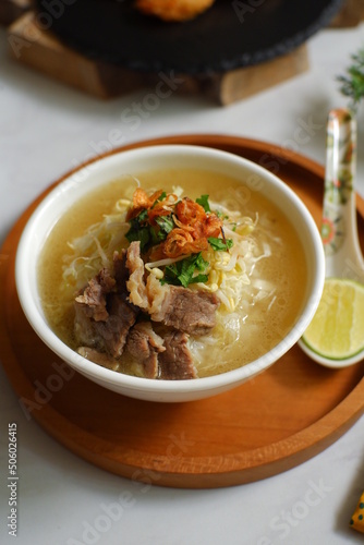 a bowl of beef vegetables clear soup served with rice named soto in Bahasa