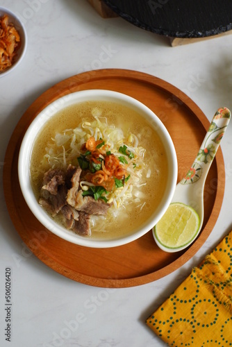 a bowl of beef vegetables clear soup served with rice named soto in Bahasa photo