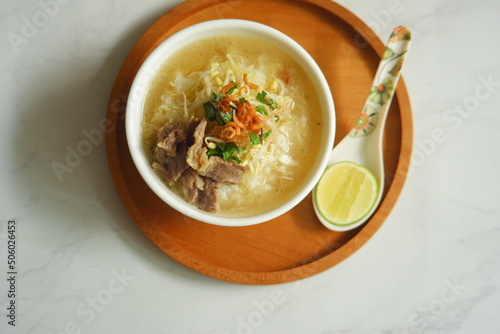 a bowl of beef vegetables clear soup served with rice named soto in Bahasa photo