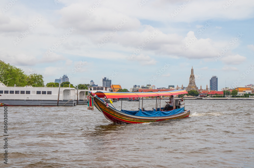 A longtail boat, the Chao Phraya River, the Thai royal first class Temple Wat Arun and the Cityscape of Bangkok Thailand Southeast Asia
