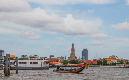 A longtail boat, the Chao Phraya River, the Thai royal first class Temple Wat Arun and the Cityscape of Bangkok Thailand Southeast Asia