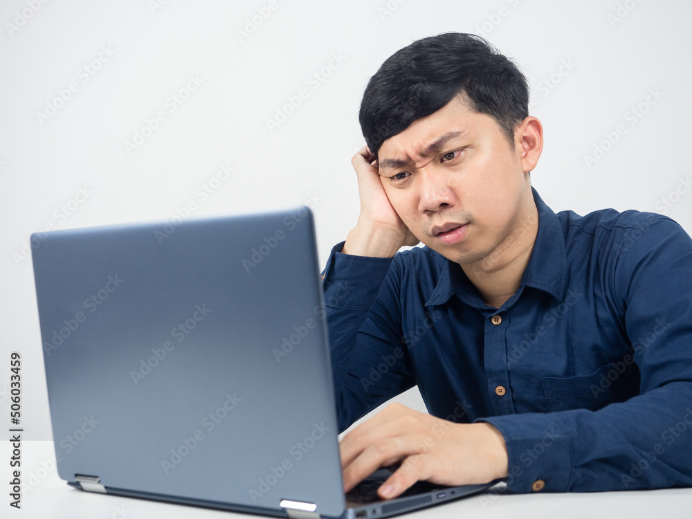 Male employee sitting at office workspace feeling strain looking at laptop Male employee sitting at office workspace feeling strain looking at laptop