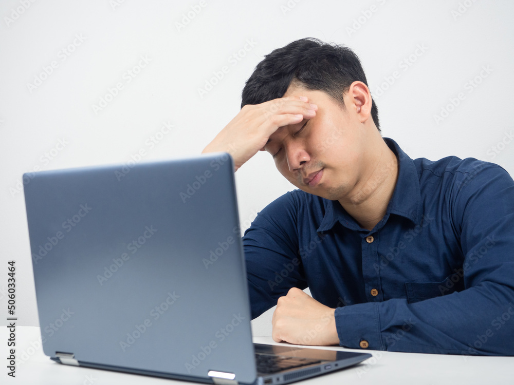 Male employee sit with laptop feeling tried and headache with work Male employee sit with laptop feeling tried and headache with work