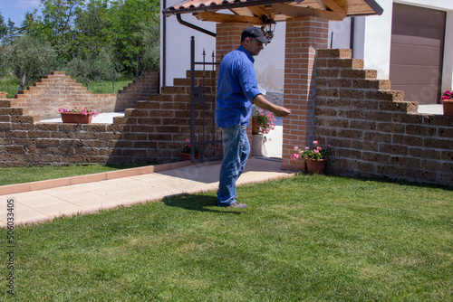 Photo of a gardener who manually fertilizes the lawn in his home garden