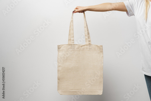 Female hand holding eco or reusable shopping bag against white background photo