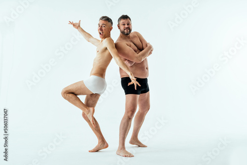 Two multiethnic men posing for a male edition body positive beauty set. Shirtless guys with different age, and body wearing boxers underwear