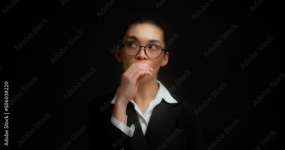 Businesswoman in glasses and office clothes experiences a coughing from vaping on isolated black background.Asian woman smokes an electronic cigarette.Nicotine addiction, harmful habit, health hazard. Businesswoman in glasses and office clothes experiences a coughing from vaping on isolated black background.Asian woman smokes an electronic cigarette.Nicotine addiction, harmful habit, health hazard.