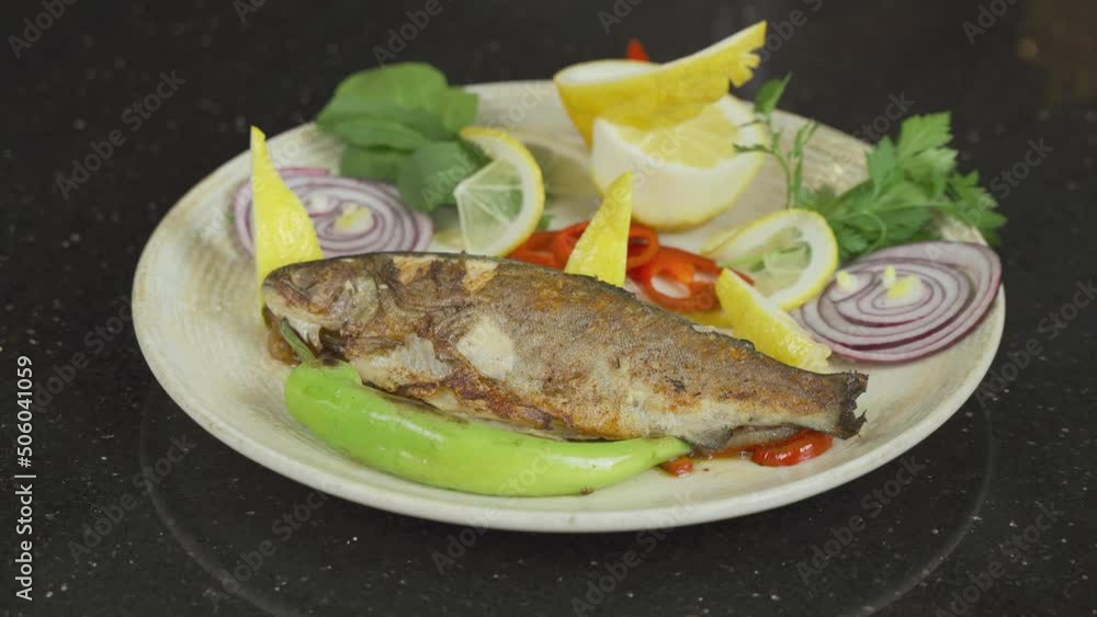 Fish serving platter.
Fish serving platter is placed on the table. The chef puts lemon slices on the fish among the green vegetables.
Fish serving platter.
Fish serving platter is placed on the table. The chef puts lemon slices on the fish among the green vegetables.