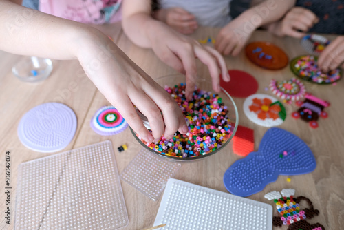 Fototapeta close-up of children's hands creating perler bead patterns, make crafts using th