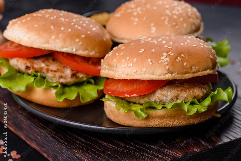 Three hamburger with beef meat burger and fresh vegetables on dark background Three hamburger with beef meat burger and fresh vegetables on dark background