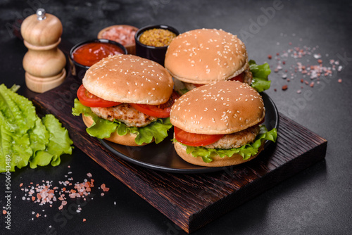 Three hamburger with beef meat burger and fresh vegetables on dark background