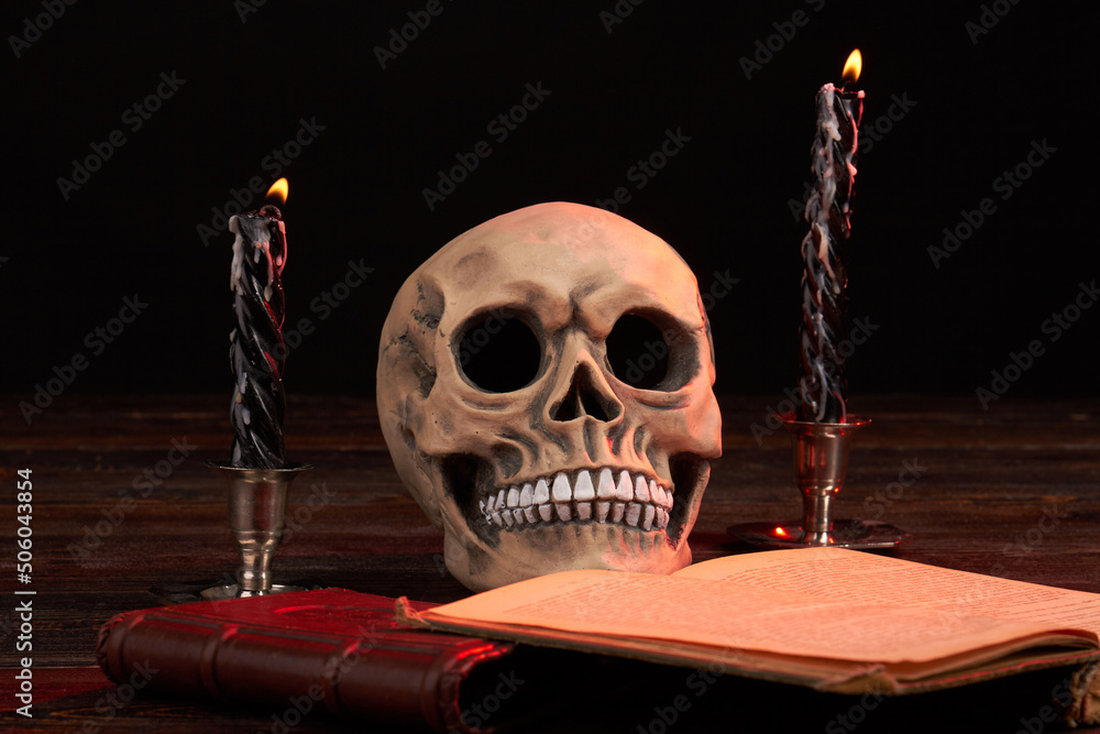 Satanic composition of humans skull with satanic book and burning candles. Rithual with opened satanic bible. Satanic composition of humans skull with satanic book and burning candles. Rithual with opened satanic bible.