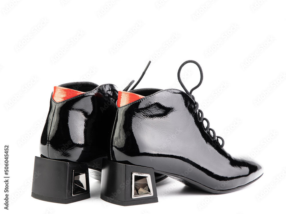 Women's autumn ankle black leather boots with black zip and average heels, isolated white background. Back side view. Fashion shoes.