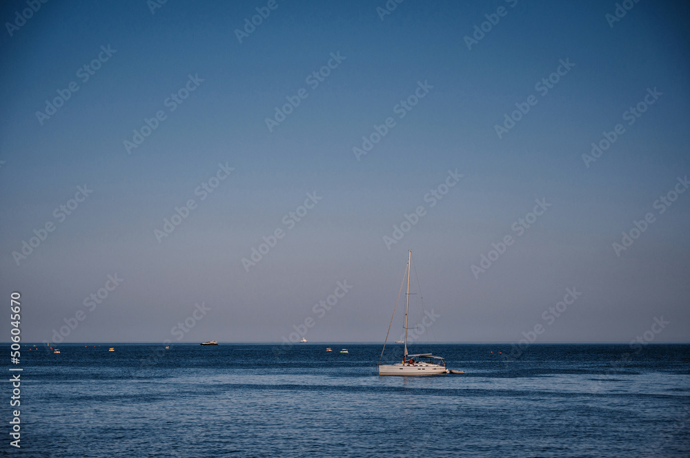 white sailing yacht stands in a bay on sea on sunny summer day with a blue sky