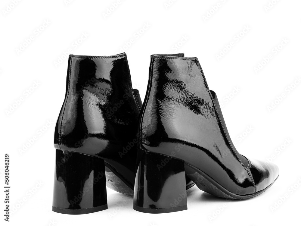 Women's autumn ankle black leather boots with black zip and average heels, isolated white background. Back side view. Fashion shoes.