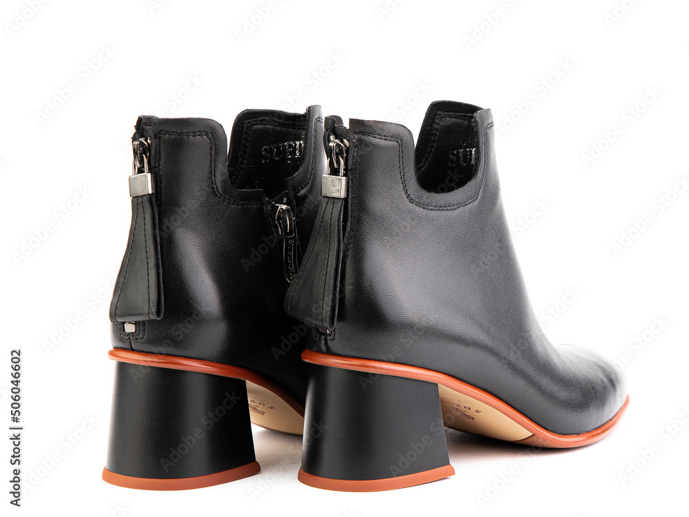 Women's autumn ankle black leather boots with zip and average heels, isolated white background. Back side view. Fashion shoes.