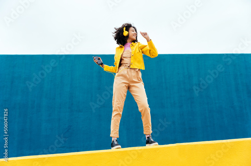 Young woman having fun outdoor in Barcelona. Hispanic female model dancing and listening to music. Representation of carefree and lifestyle concepts	