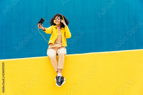 Young woman having fun outdoor in Barcelona. Hispanic female model dancing and listening to music. Representation of carefree and lifestyle concepts	