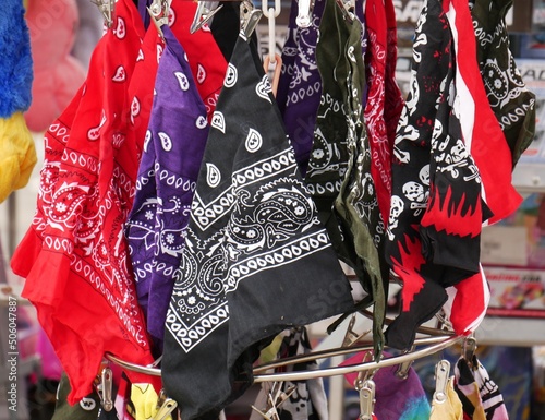 Foulards bandana au couleurs rouge, noir et violet suspendus sur un présentoir de marché