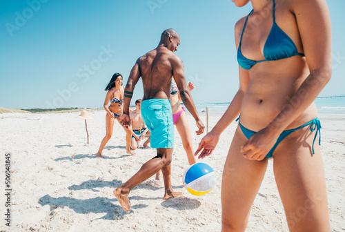 Group of friends spending time on the beach together celebrating. People enjoying the mediterranean sea and the nature. Concept about vacations and lifestyle