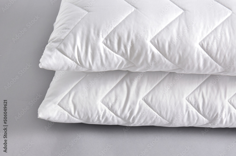 Obraz premium Stack of white soft pillows on gray background