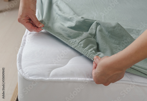 Woman puts menthol sheets on the bed. Sheet on an elastic band top view