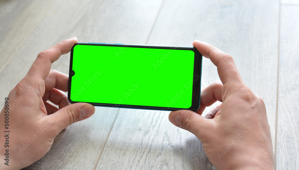 A man holds a smartphone with a green screen.Mockup. Copy space for text A man holds a smartphone with a green screen.Mockup. Copy space for text