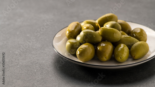 Large green pickled olives on a dark gray background, close-up