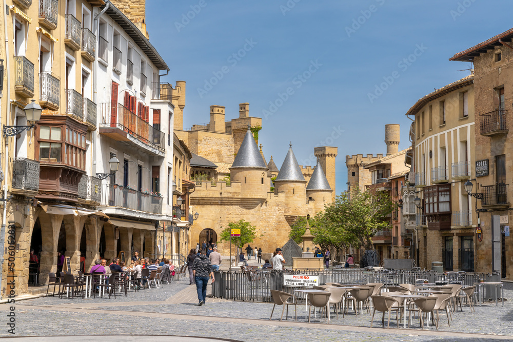 tourists enjoy a visit to historic Olite on a beautiful summer day with the Palacio Real castle in the background