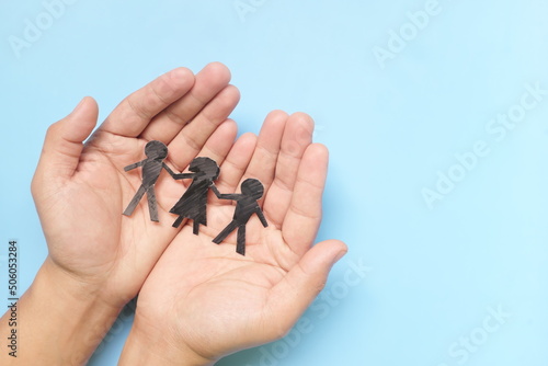 Hand holding children paper cutout. Child abuse rehabilitation, custody, human rights and refugee care and protection concept.