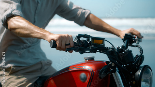 European young man hold motorbike handlebars while touching gas handle and brake lever ahead of trip