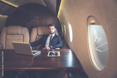 Businessman flying on his private jet. Business man flying on the private airplane. Working during the flight to his meeting. Concept about transportations and salespeople  photo