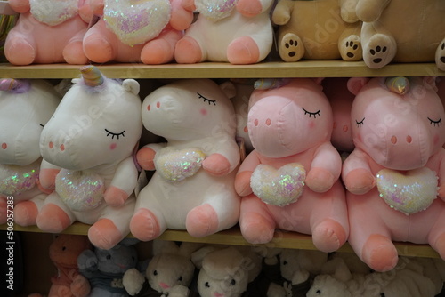 Unicorn plush toys in a store shelf for sale. Cute soft unicorn. Childrens girly pink unicorn stuffed animal plush toy. White Unicorn plush figure and many Colorful plush toys.