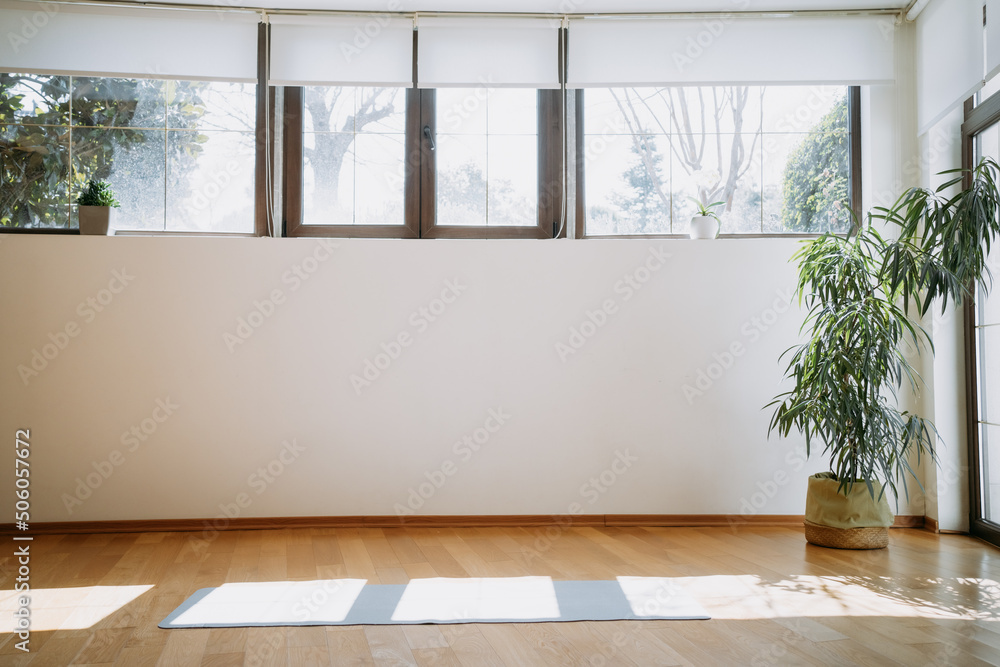 Side view of the grey foam yoga or pilates mat laying on natural wooden floor during the sunny day. Sport and recreation concept