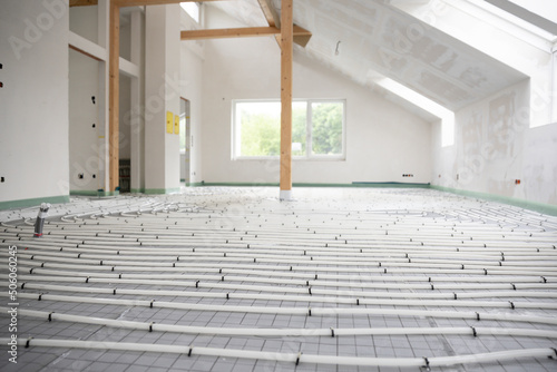 Shot of construction site in a loft where underfloor heating has just been installed, white pipes on grey mat