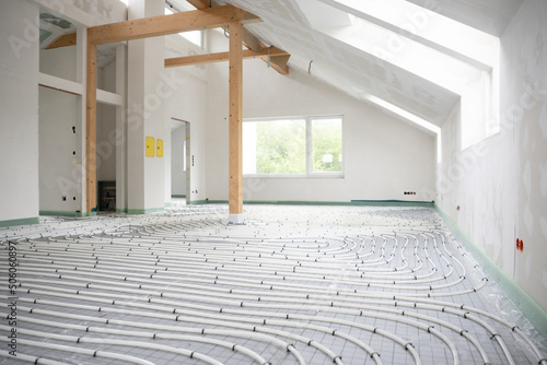 Shot of construction site in a loft where underfloor heating has just been installed, white pipes on grey mat