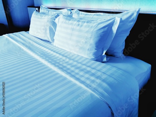 bed with pillows in room that have light from neon on head bed