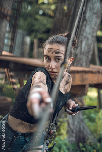 Fotografiet Young woman holding sharp bayonet knife in forest