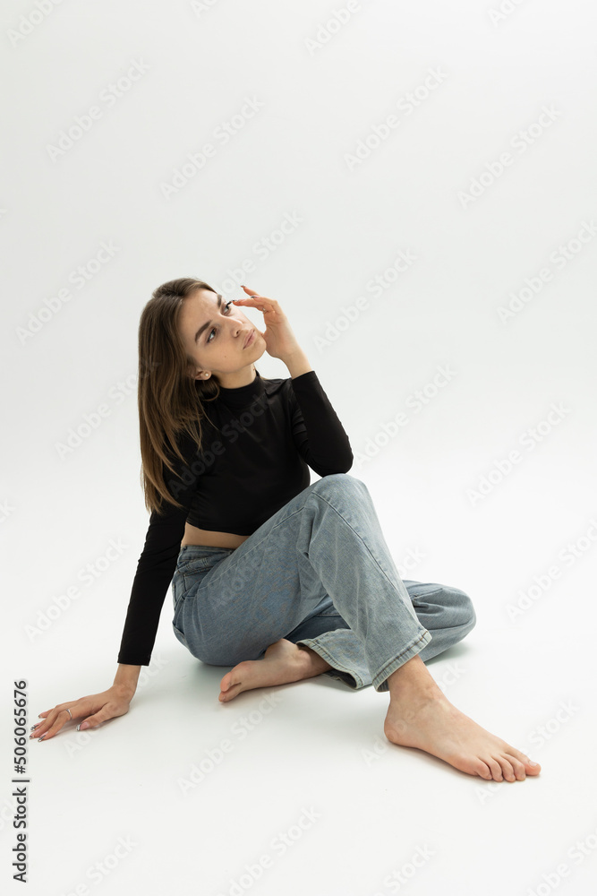 beautiful, sexy, slim woman posing sitting on a light background in fashionable jeans and a T-shirt beautiful, sexy, slim woman posing sitting on a light background in fashionable jeans and a T-shirt