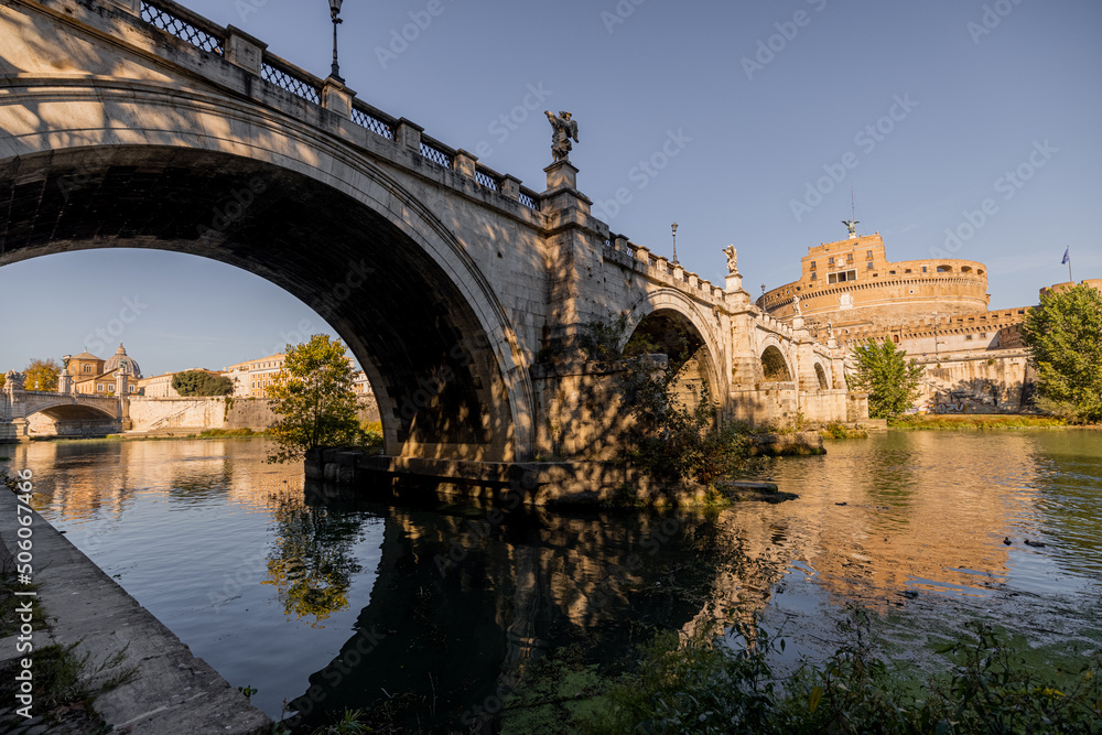 Landscape of Tiber river with old arch bridge at sunny morning in Rome. Dome of famous saint Peter basalica on the skyline. Traveling Italy