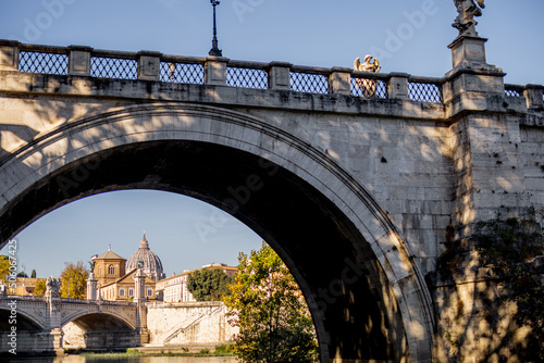 Landscape of Tiber river with old arch bridge at sunny morning in Rome. Dome of famous saint Peter basalica on the skyline. Traveling Italy photo